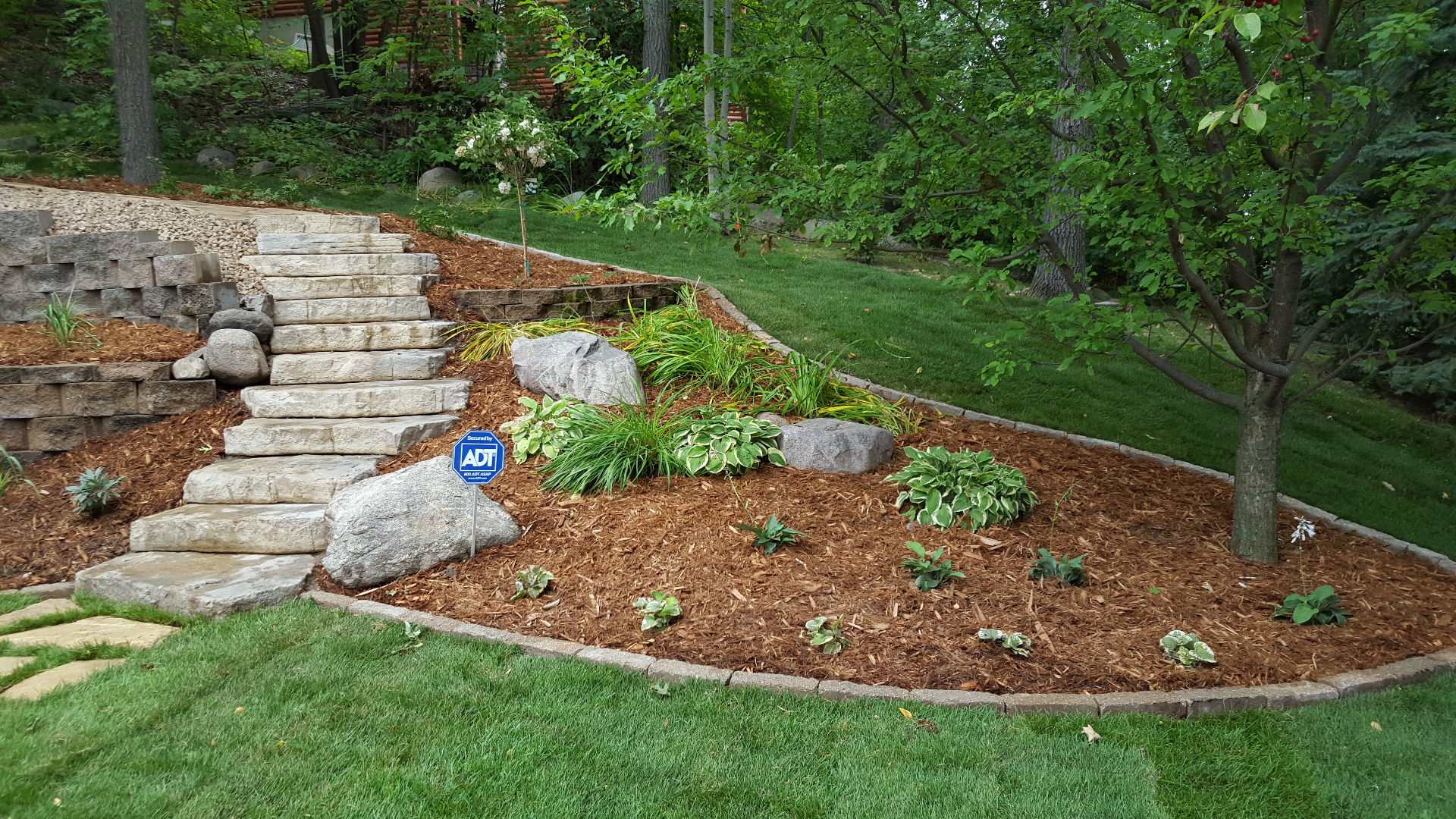 Stone staircase with landscaped mulched bed and hosta plantings