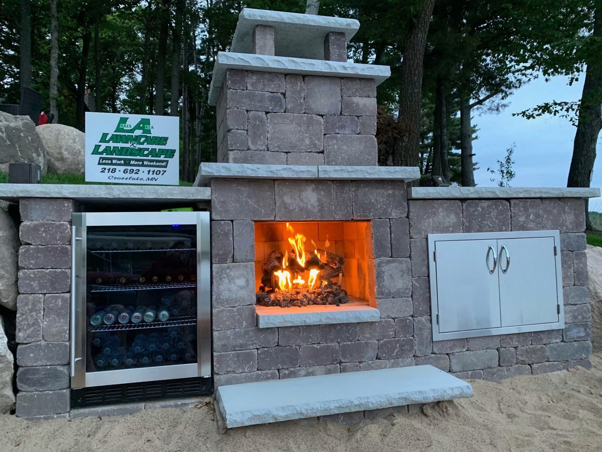 Custom stone outdoor fireplace with built-in beverage cooler