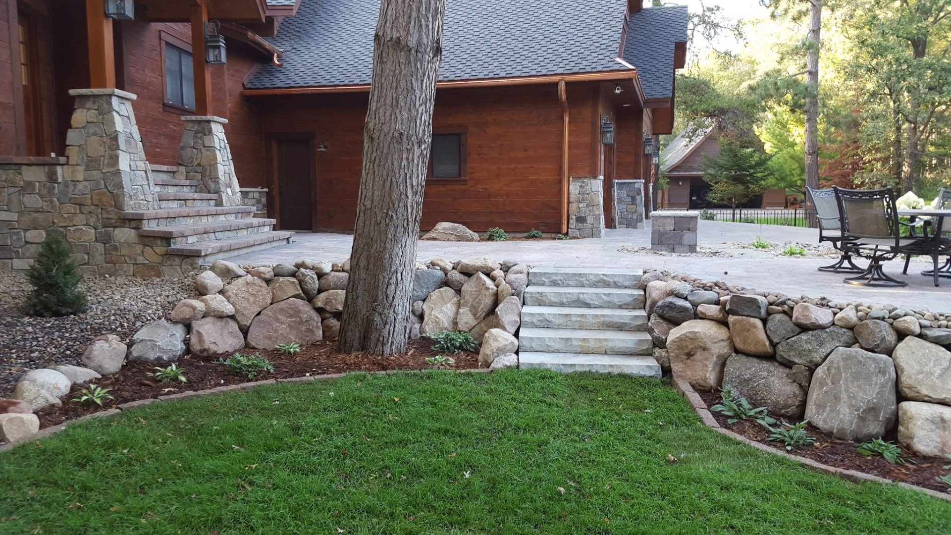 Boulder retaining wall with bluestone steps and paver patio