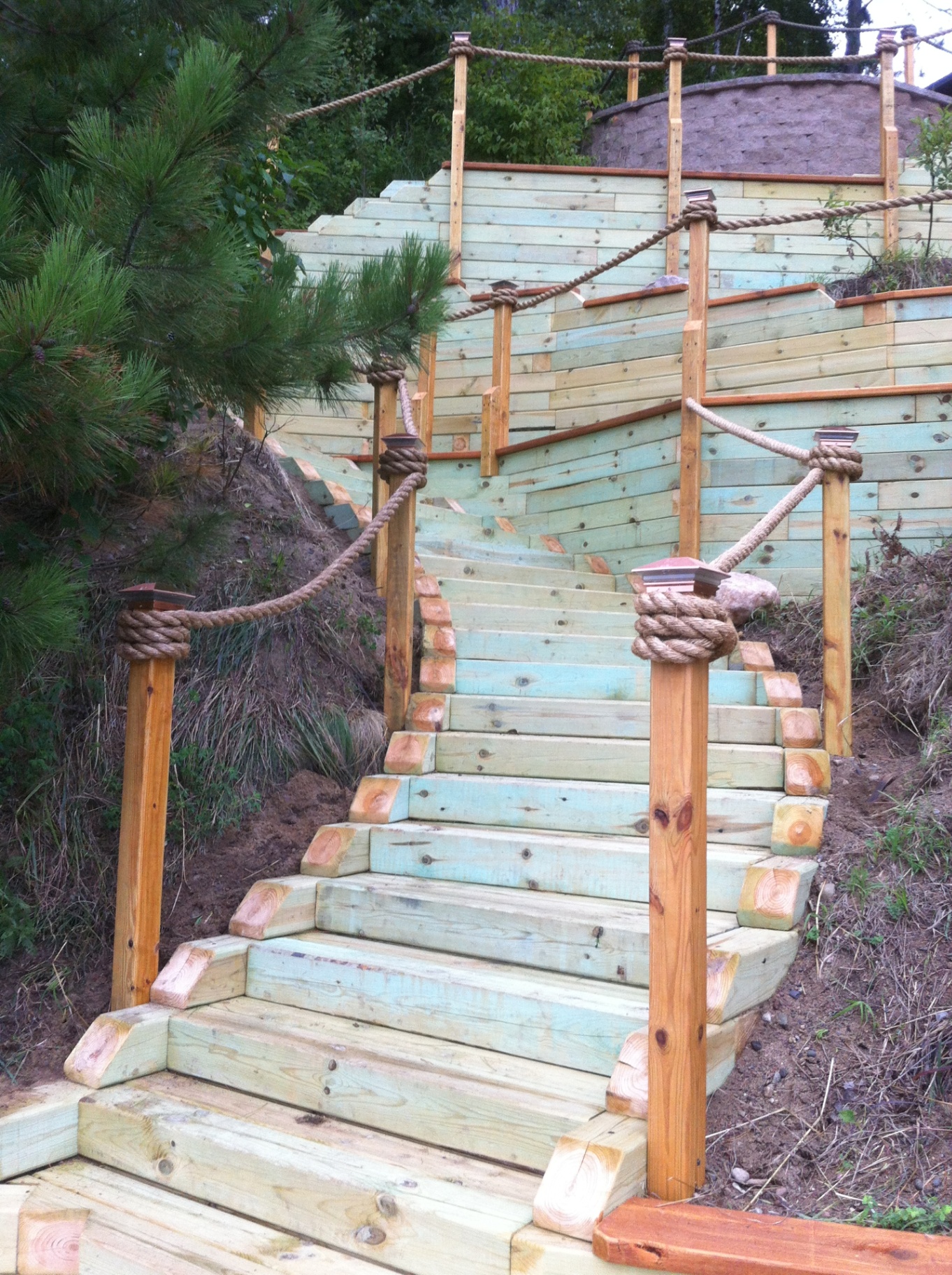Timber staircase with rope railings up steep wooded hillside